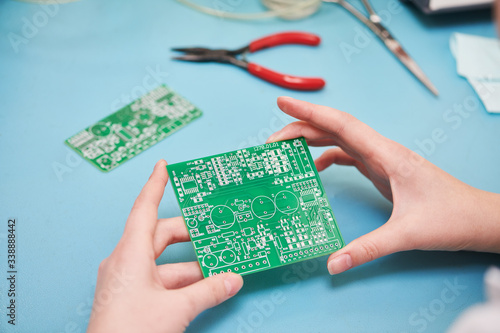 Microcontroller circuit board manufacture. Technician's hand with pcb