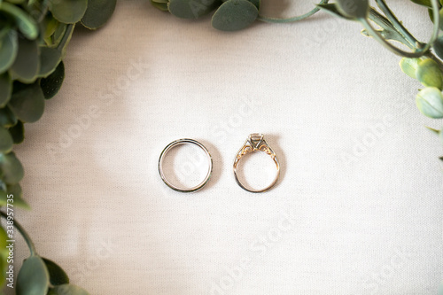 Wedding bands on a white clothe surrounded by leaves