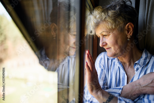 Sad senior woman standing indoors at home, corona virus and quarantine concept.