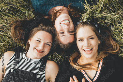 drei Freundinnen liegen Kopf an Kopf auf der Wiese