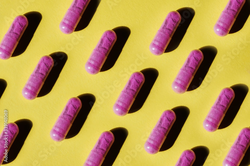 Pattern of purple pill capsules on a yellow background. Background and texture for the concept of unusual abstract medicines for the treatment of diseases and symptoms