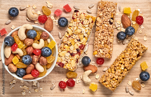 Cereal healthy snack. Granola bar with nuts and dry fruit berries. Diet food. Protein muesli bars isolated on wood background. Sport oatmeal bar, top view, closeup