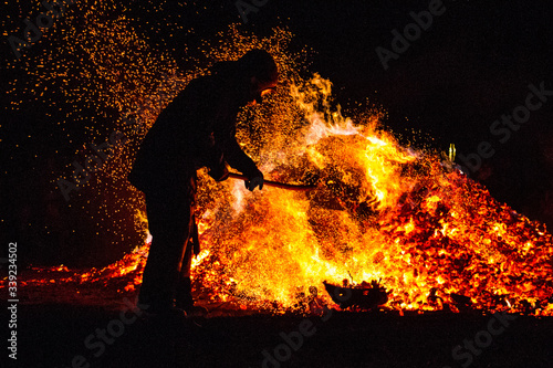 Man shuffles wood into the fire