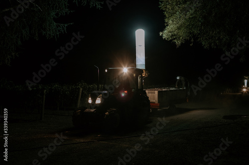 Harvest workers and tractor at dawn in vineyard