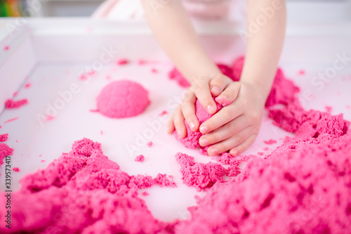 Pink magic sand in a kids hands on a white background close up. Early sensory education. Preparing for School. Development