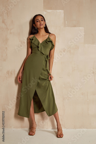 Fashion model brunette hair wear green silk dress sandals high heels accessory bag clothes for date party walk interior Sahara journey summer collection wall stairs beautiful woman sexy jewelry.