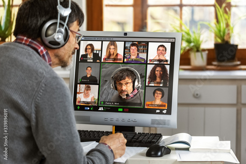 A moderator manages a video conference from his home office 