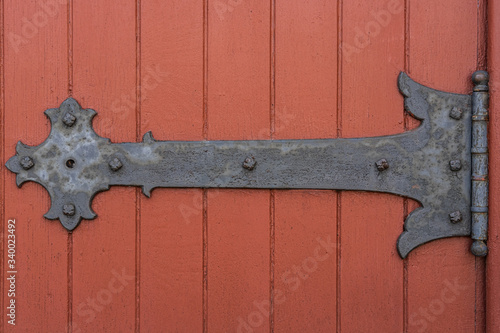 Rustic door hinge on a red painted door of an old church