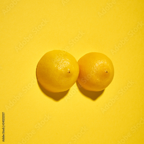 Two yellow lemons on a bright yellow background, imitation of a beautiful female breast.
