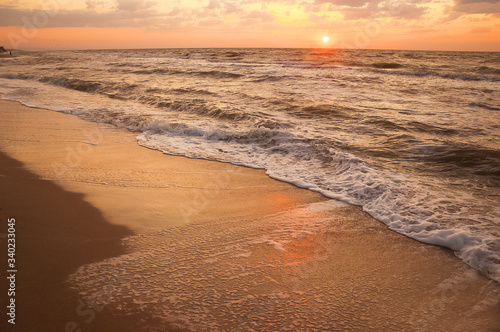 Natural background for text and sand and sea waves. Footprints in the sand from the legs go into the distance. Summer, sea, sunrise.
