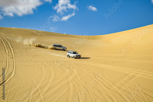 Two Vehicles Racing through the Desert Dunes of Siwa Oasis in Sunny Day, Desert Safari