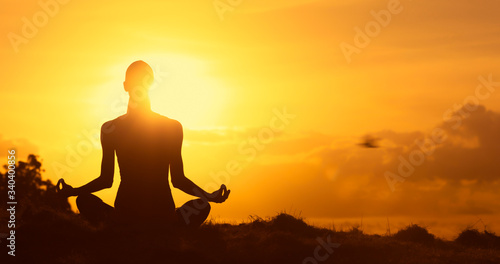 Meditation silhouette of you female sitting facing the beautiful sunrise. 