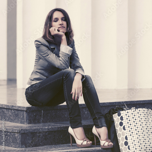 Young fashion woman in gray blazer sitting on steps