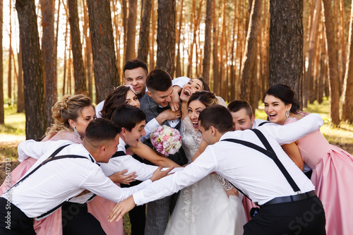 Happy wedding, group of bridesmaids, groomsmen, bride and groom having fun and embracing after wedding ceremony
