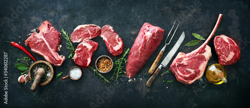 Variety of raw beef meat steaks for grilling with seasoning and utensils