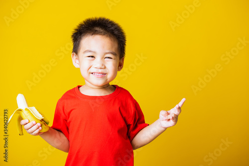 kid cute little boy attractive smile wearing red t-shirt playing holds peeled banana for eating
