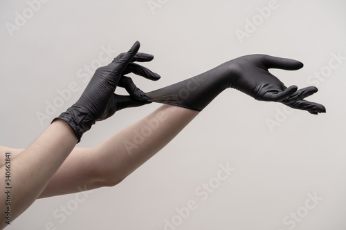 Hands in black silicone gloves on a light background.