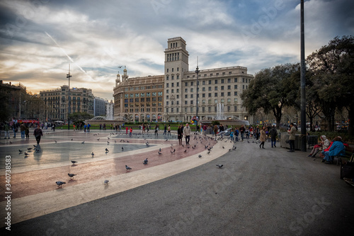 Tourists feed the pigeons on the Square of Catalonia (Placa de Catalunya) in Barcelona. Plaza de Catalunya is one of the main attractions of the Catalonia capital.