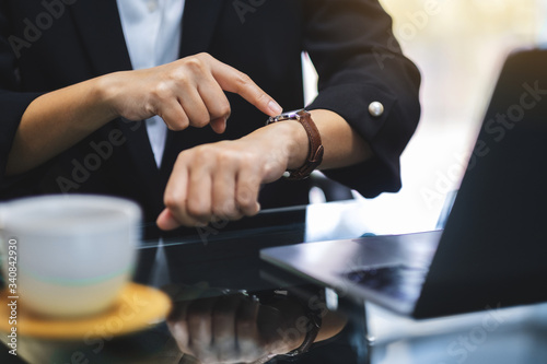 A business woman pointing at a wristwatch on her working time while waiting for someone in office