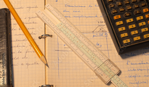 Pencil, old slide rule and scientific electronic calculator page with the calculations in progress