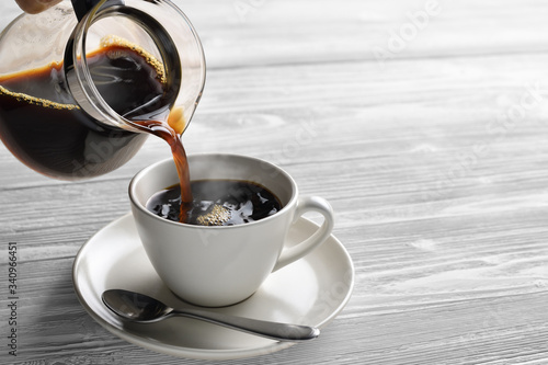 Pouring coffee with smoke on a cup on wooden background