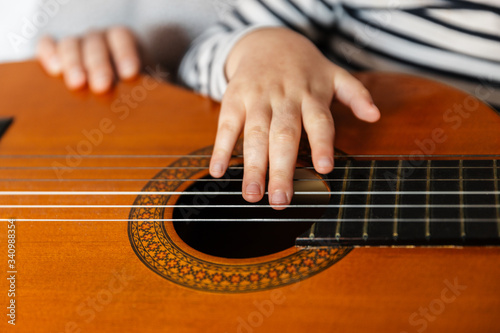 niño juega y aprende con una mujer a tocar la guitarra en la cama. son madre e hijo, él tiene una pluridiscapacidad. Actividad sensorial. están alegres y riendo. instrumento de música. educación.