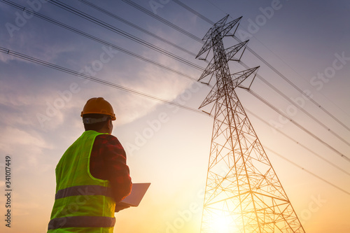 Asian Manager Engineering in standard safety uniform working inspect the electricity high voltage pole.