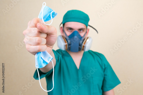 Doctor holds medical mask on the yellow background defocused.