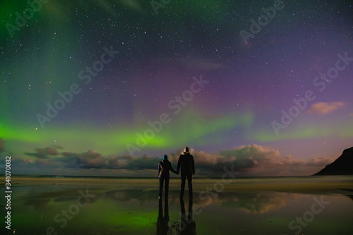 people on the beach and aurora in norway, lofoten islands