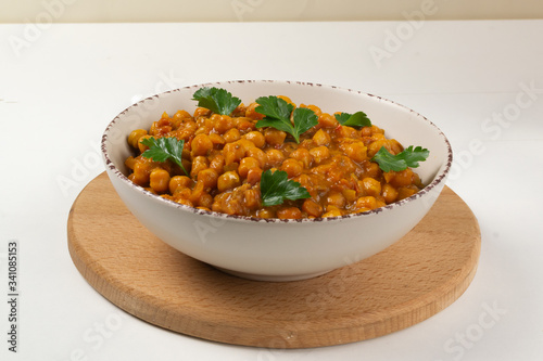 Chana masala in a creamy deep plate on a white background. A traditional dish of Indian cuisine. Copy space.