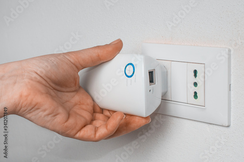 Woman plug a wifi repeater on a wall plug