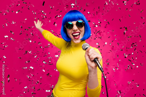 Low angle view photo of nice lady singer night club party hold microphone karaoke sound confetti fall wear specs yellow turtleneck blue short wig isolated bright pink color background