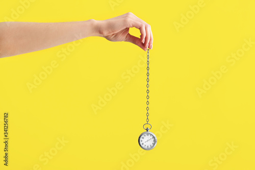 Female hand with pocket clock on color background. Time management concept