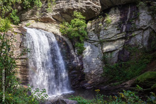 Beautiful summer landscape with a waterfall. A large waterfall among the huge cliffs overgrown with trees. Looking Glass Fall, NC, USA