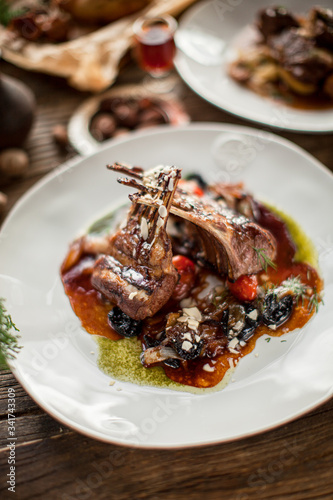 Plate with grilled ribs with sauce haute cuisine on wooden table in sunny daylight