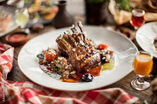 Plate with grilled ribs with sauce haute cuisine on wooden table in daylight restaurant