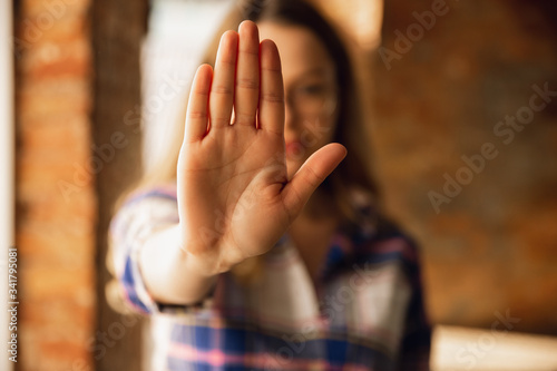 Close up view of young woman making stop gesture with her hand. Cropped isolated portrait of caucasian female model. Showing her position, rejecting, defending. Copyspace for advertising.