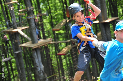 Summer camp. Radość dziecka podczas zabawy z innymi dziećmi w parku linowym na obozie sportowym letnim