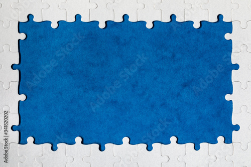 Framing in the form of a rectangle, made of a white jigsaw puzzle. Frame text and jigsaw puzzles. Frame made of jigsaw puzzle pieces on blue background.