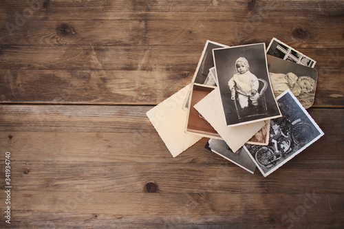 old vintage monochrome photographs in sepia color are scattered on a wooden table, the concept of genealogy, the memory of ancestors, family ties, memories of childhood