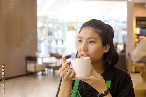 asian woman barista holding coffee cup to test and drinking at cafe