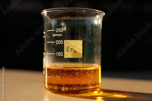 A chemical reaction to produce liquid bromine in a beaker, in the sunlight.