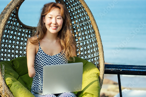 happy asian freelancer businesswoman using a laptop in summer vacation on beach tropical resort.freelance and remote work concept on sea