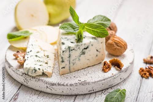 Segment of blue mould cheese - Gorgonzola with pear and walnuts on wooden board. Top view