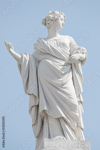 Ancient top roof statue of sensual Italian Renaissance and Rococo Era half naked woman as artist in Potsdam at blue sky, Germany, details, closeup