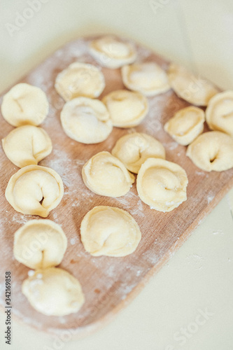 freshly molded homemade dumplings lie on a wooden board. A photo of the cooking process.