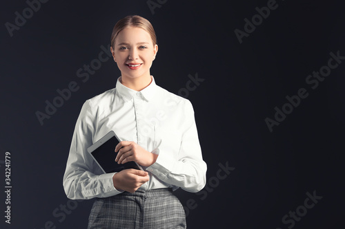 Portrait of young businesswoman with tablet computer on dark background