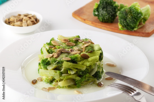 Boiled broccoli with pumpkin seeds on a white plate on the table