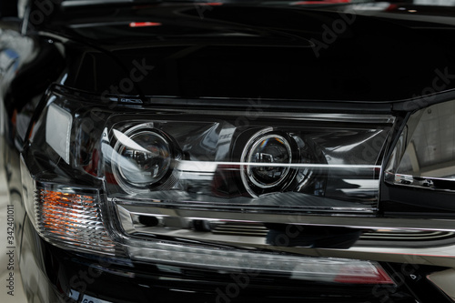 headlight of modern prestigious black car close up. Close up photo of modern car, detail of headlight. Headlight car of a modern luxury technology and auto detail. selective focus.