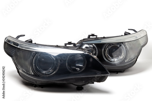A pair of xenon headlights for a German auto - optical equipment with a lens and corrector inside on a white isolated background. Spare part for replacing a front body part in a car service.